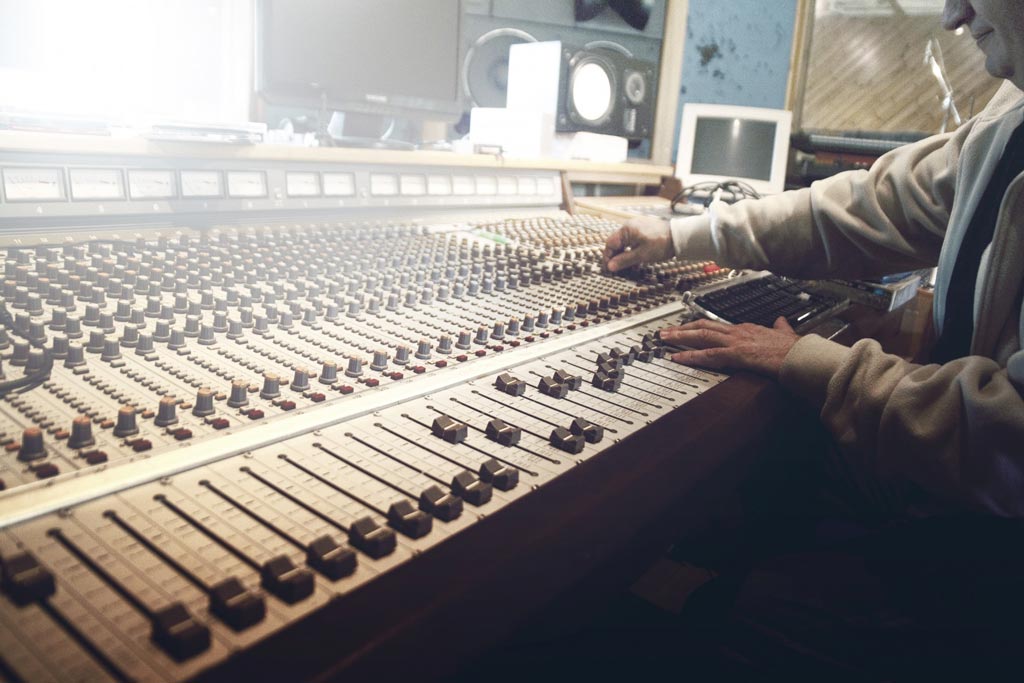 A man at a audio mixing board teaching what royalty free music is