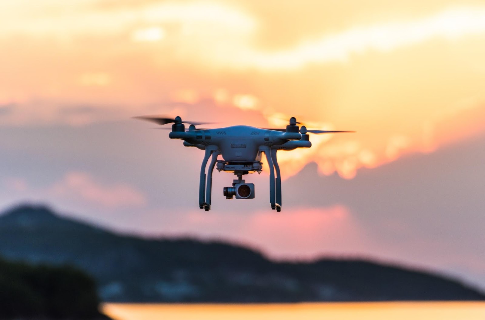 Drone with camera flying at sunset